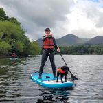 Female paddleboarder enjoying time on water with her dog.