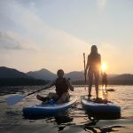 Young paddle boarders out on Derwent water with the sun going down over Causey pike