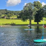 Paddle boarders enjoying a Tour on Coniston water on a sunny day.