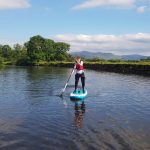 Young SUP paddler paddling down the River Derwent nr Keswick